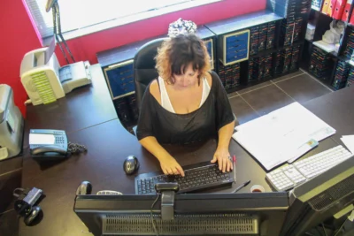 Une femme concentrée travaille sur son ordinateur dans un bureau organisé, vu d'une perspective en plongée. L’arrière-plan met en valeur un espace professionnel bien rangé, avec des classeurs et du matériel de bureau soigneusement disposés. L’angle de vue offre une dynamique intéressante, mettant en avant l’implication et le sérieux du travail en cours. - Agrandir l'image 22 sur 28, fenêtre modale